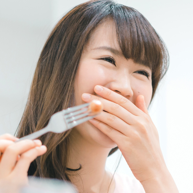 口元を手で隠して笑う女性の写真