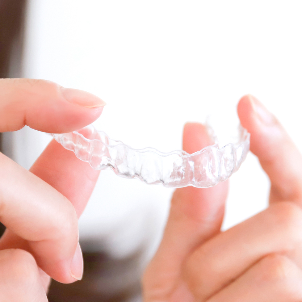 矯正用のマウスピースを持つ手元