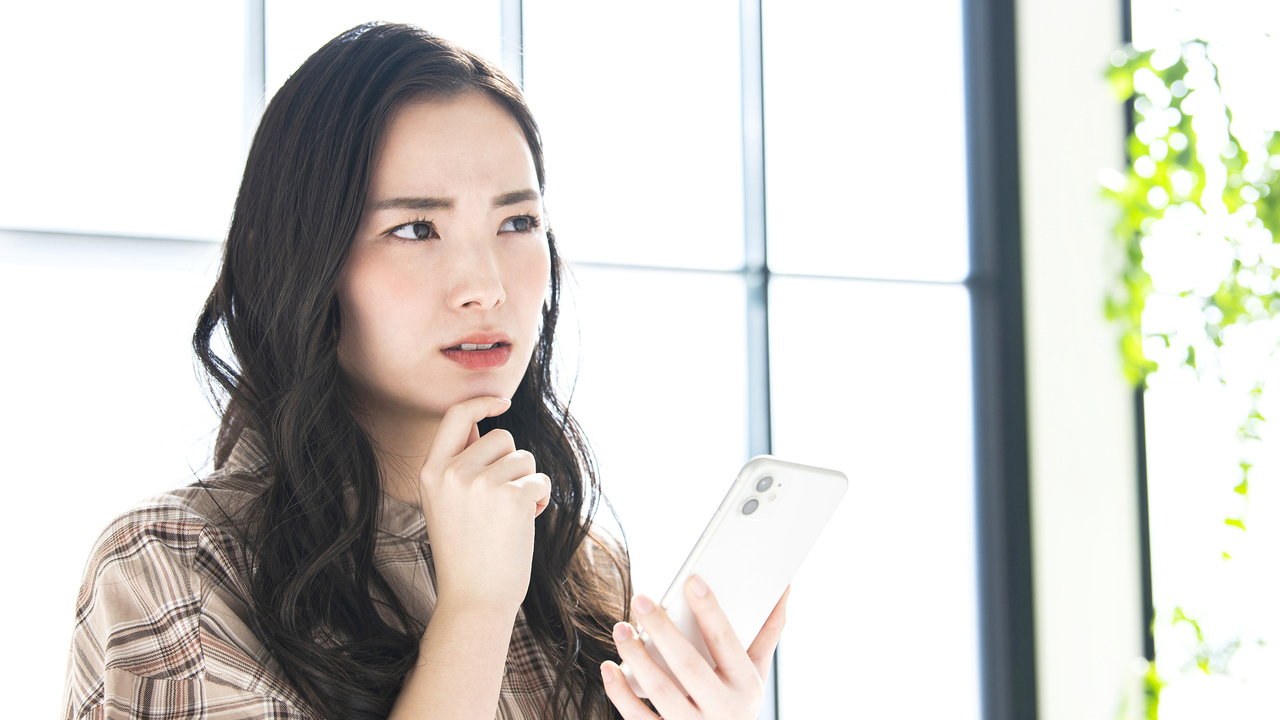 スマホを持って悩む女性