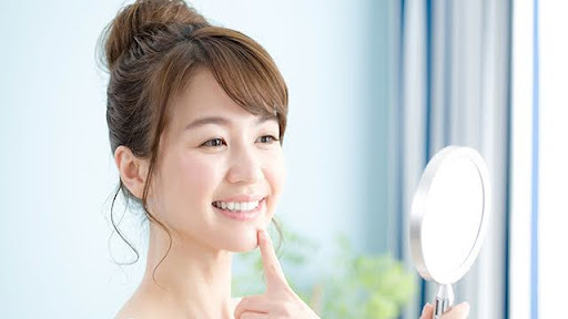 鏡を見て笑顔で歯並びを確認する女性