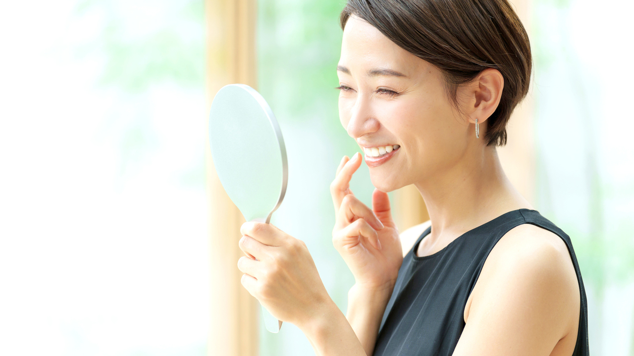 鏡を見ながら歯列矯正のメリットを実感している30代の女性