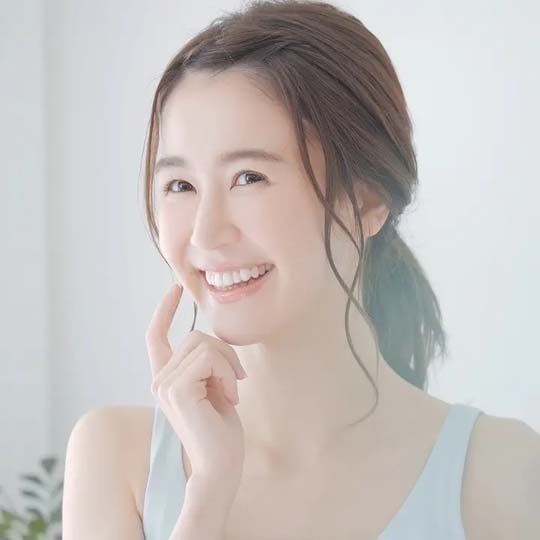 口元を指さして微笑む女性