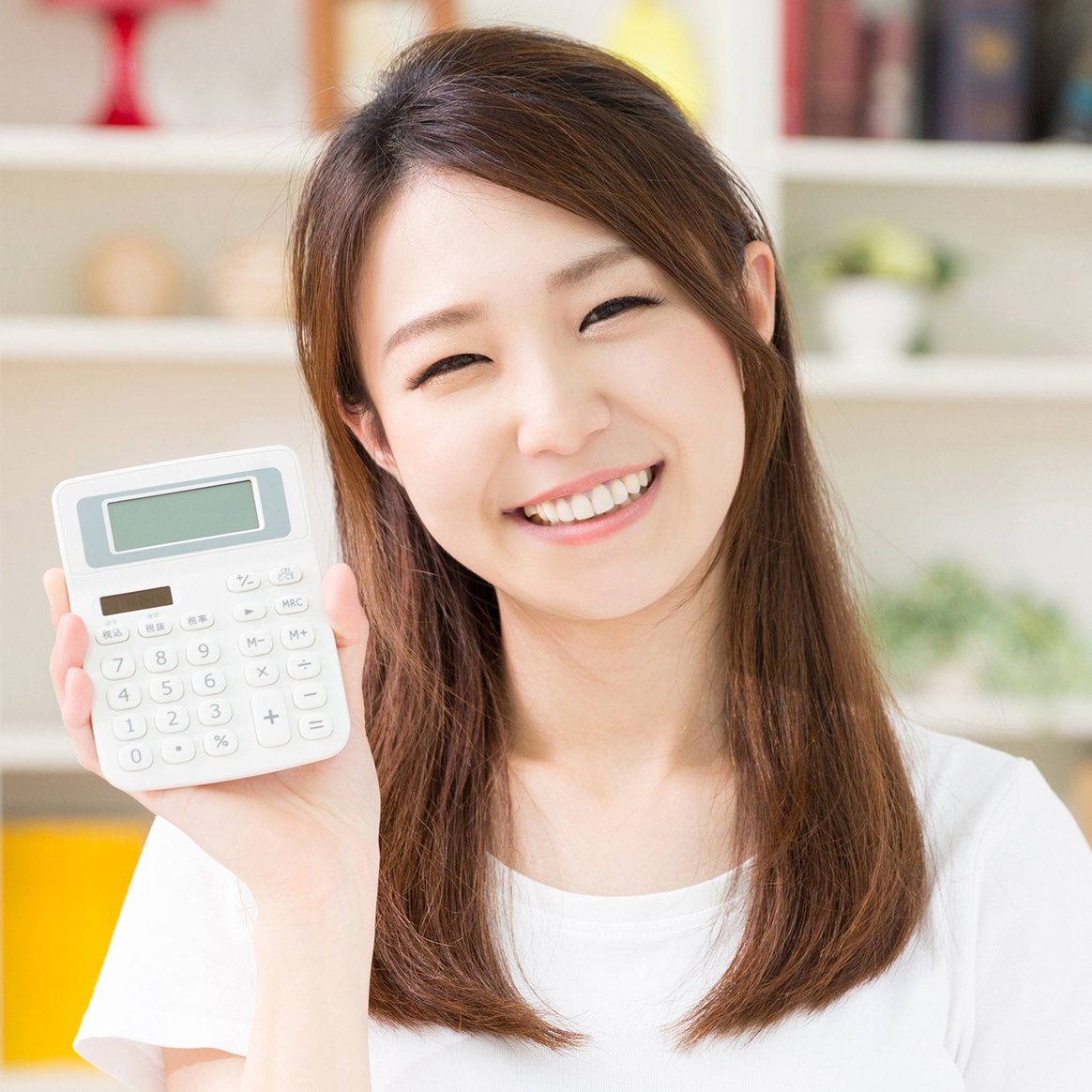 電卓を持って微笑む女性の画像