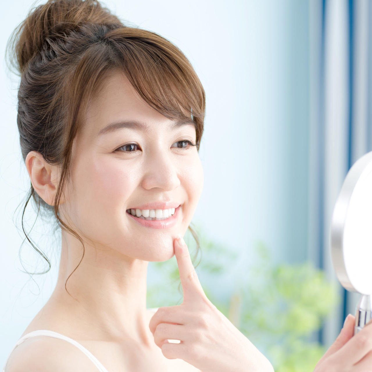 鏡で自分の歯を見て嬉しそうな女性の画像