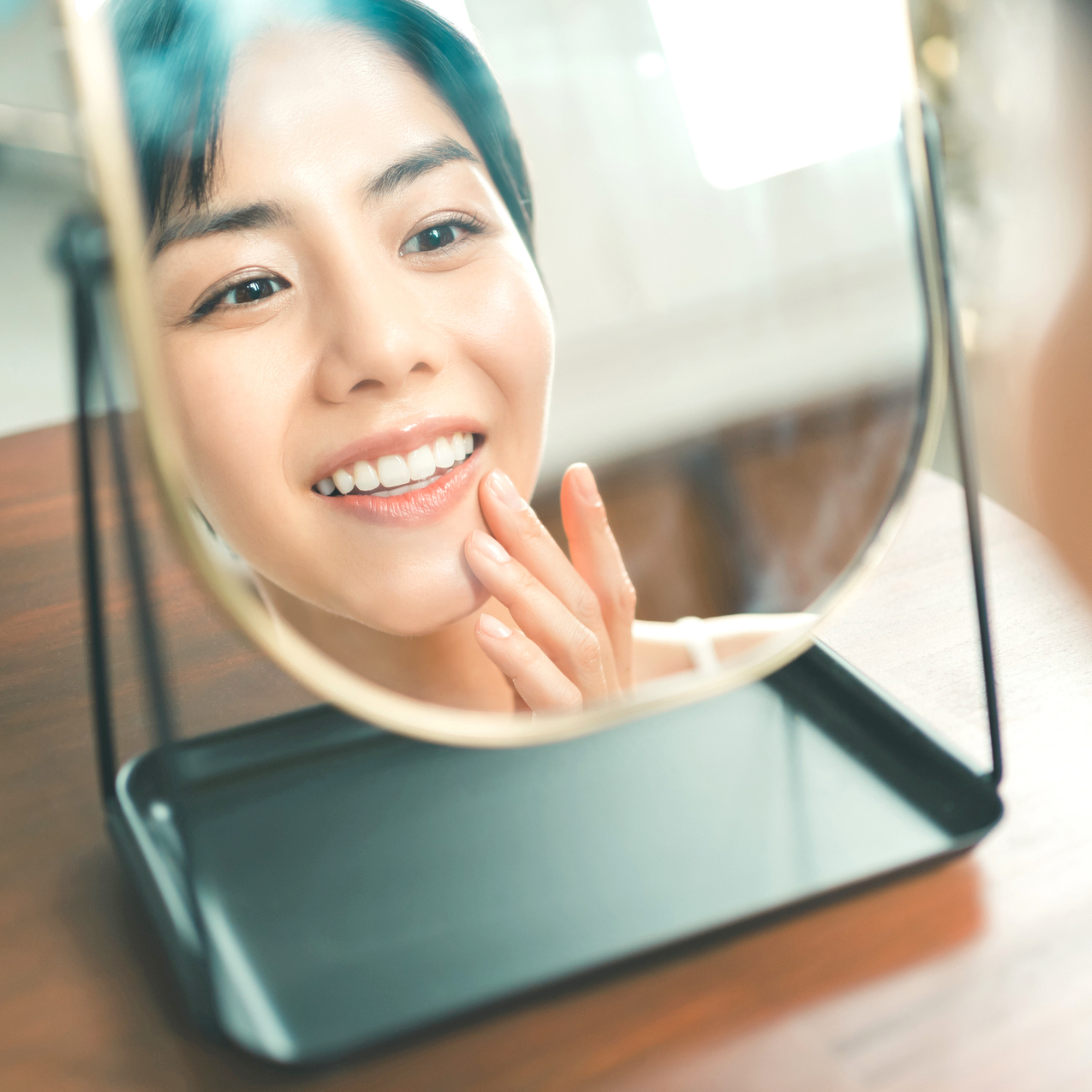 鏡を見ながら前歯のねじれを気にする30代女性